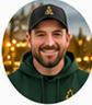 Portrait of a smiling light-skinned adult man wearing a dark baseball cap and dark green work jacket.