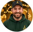 Circular portrait of a smiling man in a dark cap and dark green hoodie.